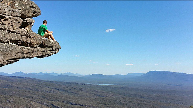 Duncan sitting on the top of a mountain looking out.